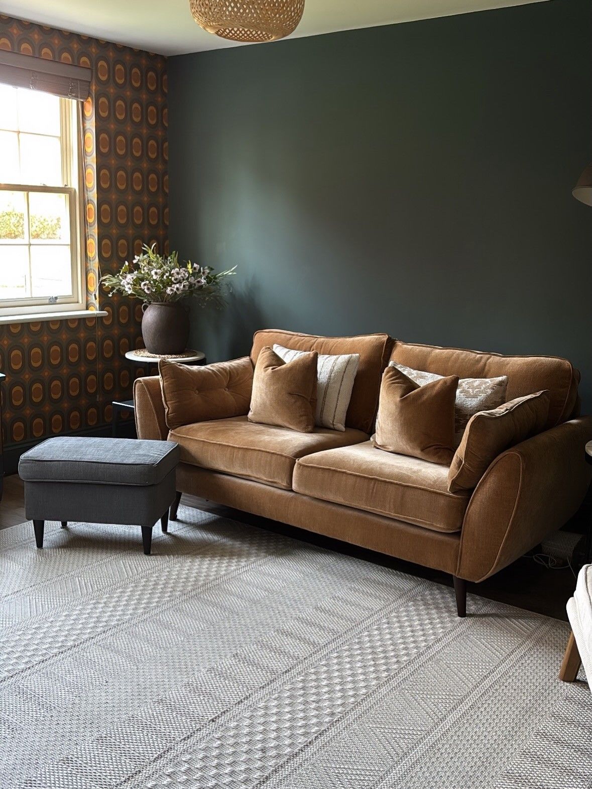 Tidy living room with velvet sofa and patterned rug