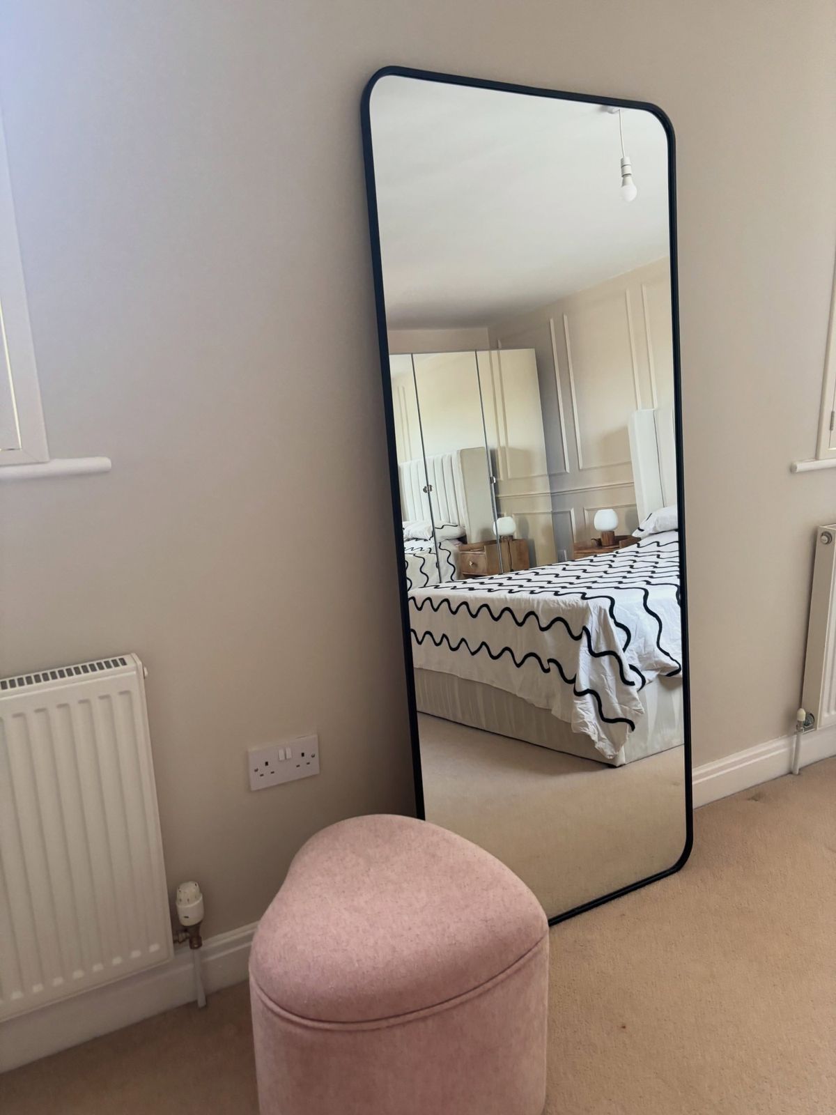 Bedroom with a full-length mirror and pink stool